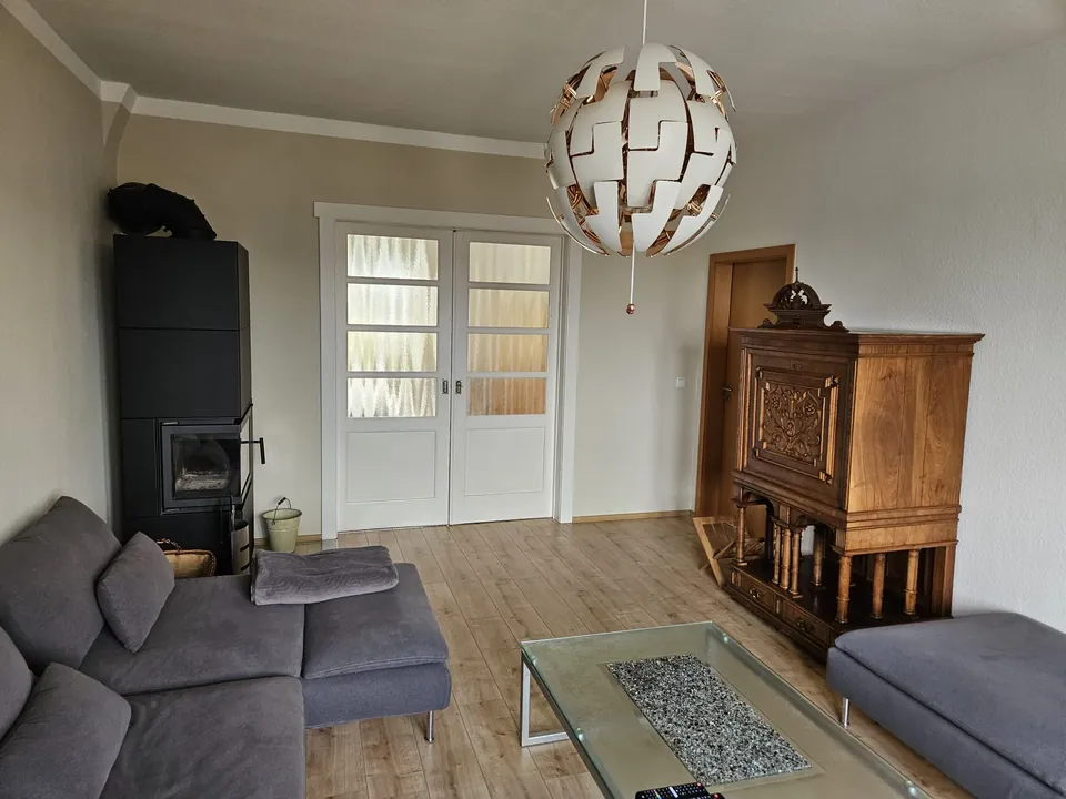 Wohnzimmer mit Kaminofen und antikem Sekretär