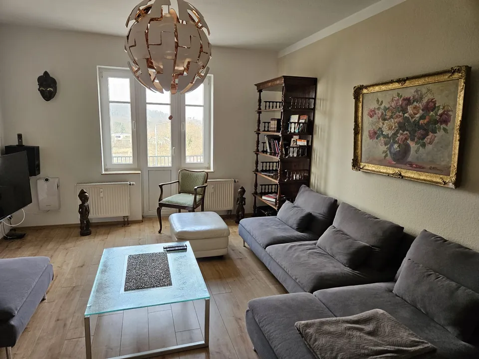 Wohnzimmer der Ferienwohnung Am Steigerwald mit großer Couch und Balkontür