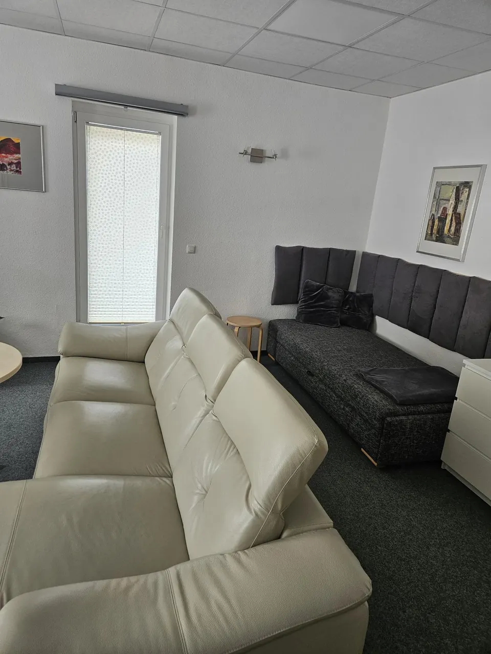 Wohnbereich mit Ledersofa und zusätzlichem, eingeklapptem Schlafsofa